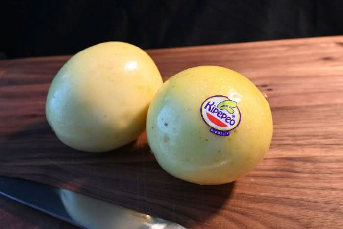 Zwei goldene Bio-Passionsfrüchte der Marke Kipepeo auf Holzbrett – Passionsfrüchte kaufen